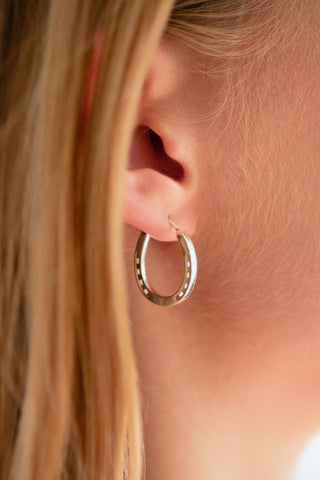 A close-up of a pair of elegant silver hoop horseshoe earrings on a blond model, placed on a marble slab, emphasizing their gleaming finish and stylish form.
Our Silver Horse Shoe Earrings are unique equestrian gifts crafted from high-quality gold. This silver horseshoe earrings are the perfect equestrian lifestyle fan gift and a good luck charm. Our Horseshoe earrings are the perfect birthday present for horse lovers, horse girls, cowgirls. A representation of good luck.