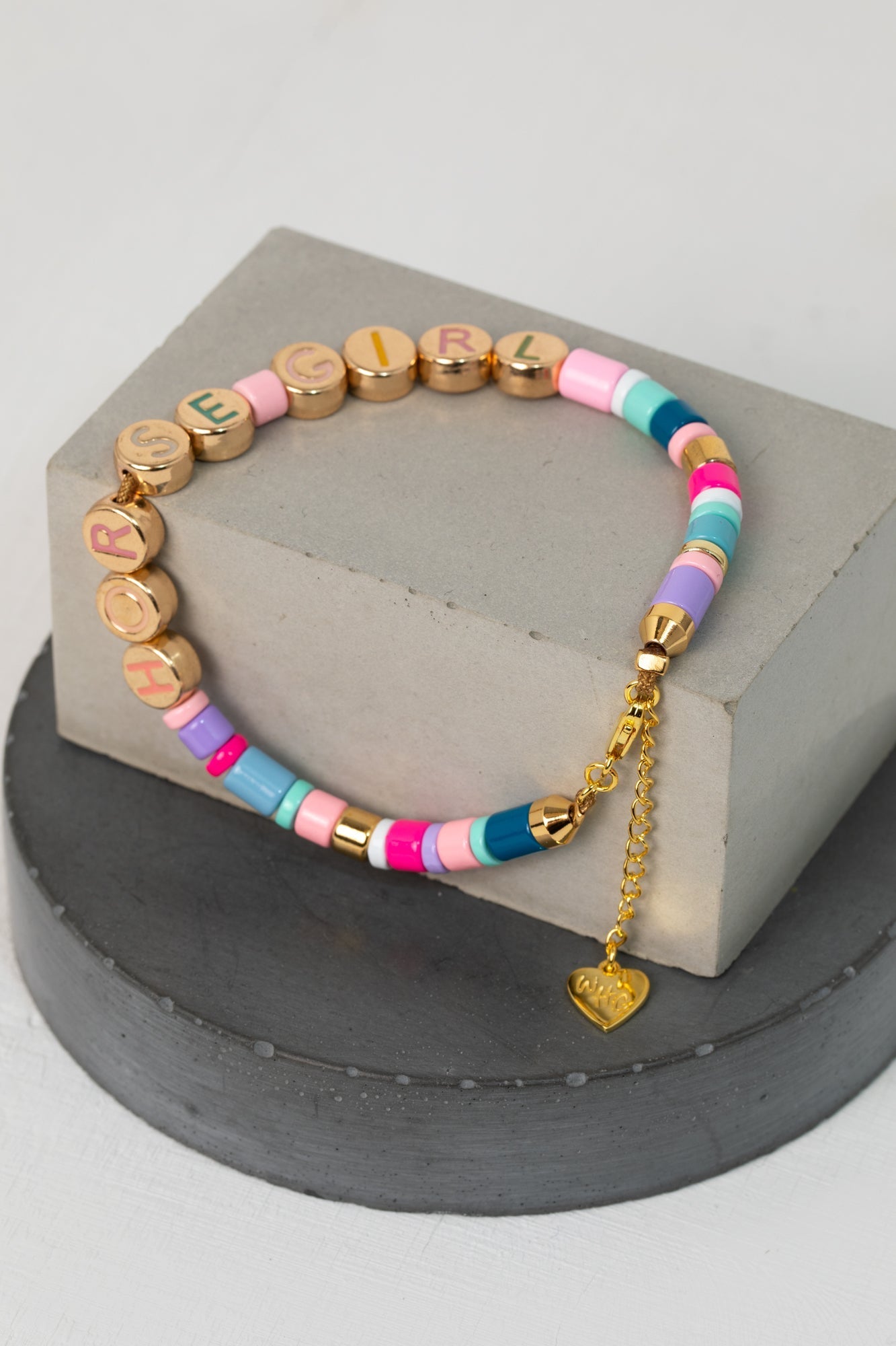 A colorful Rainbow Horse Girl Candy bracelet, complemented by a stylish gold charm, showcasing a unique design, text: Horse Girl. An eclectic jewelry great for horse lover gifting, equestrian gifts for women,  cool equestrian gifts, gold jewelry girls.
Our bracelet is much like the friendship bands BFF, with colored beads and a gold chain that ends with a heart charm with the engraved initials of WHC: Wild Horse Club.