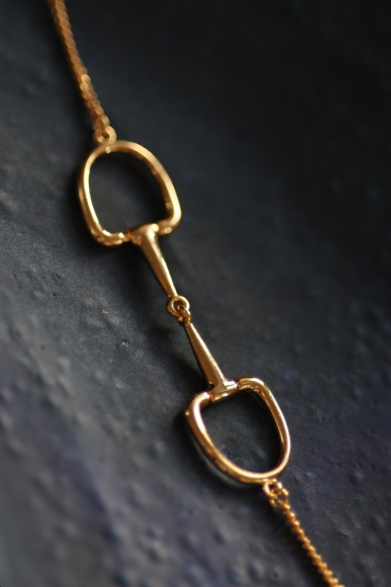 Close up of a stylish gold Snaffle Bit Necklace embodying sophistication in its design.  Perfect for horse enthusiasts and fashion lovers, it adds a refined touch to any outfit and makes a memorable equestrian gifts for women and horse themed gifts. Featuring a stunning snaffle bit pendant crafted from high-quality gold. 