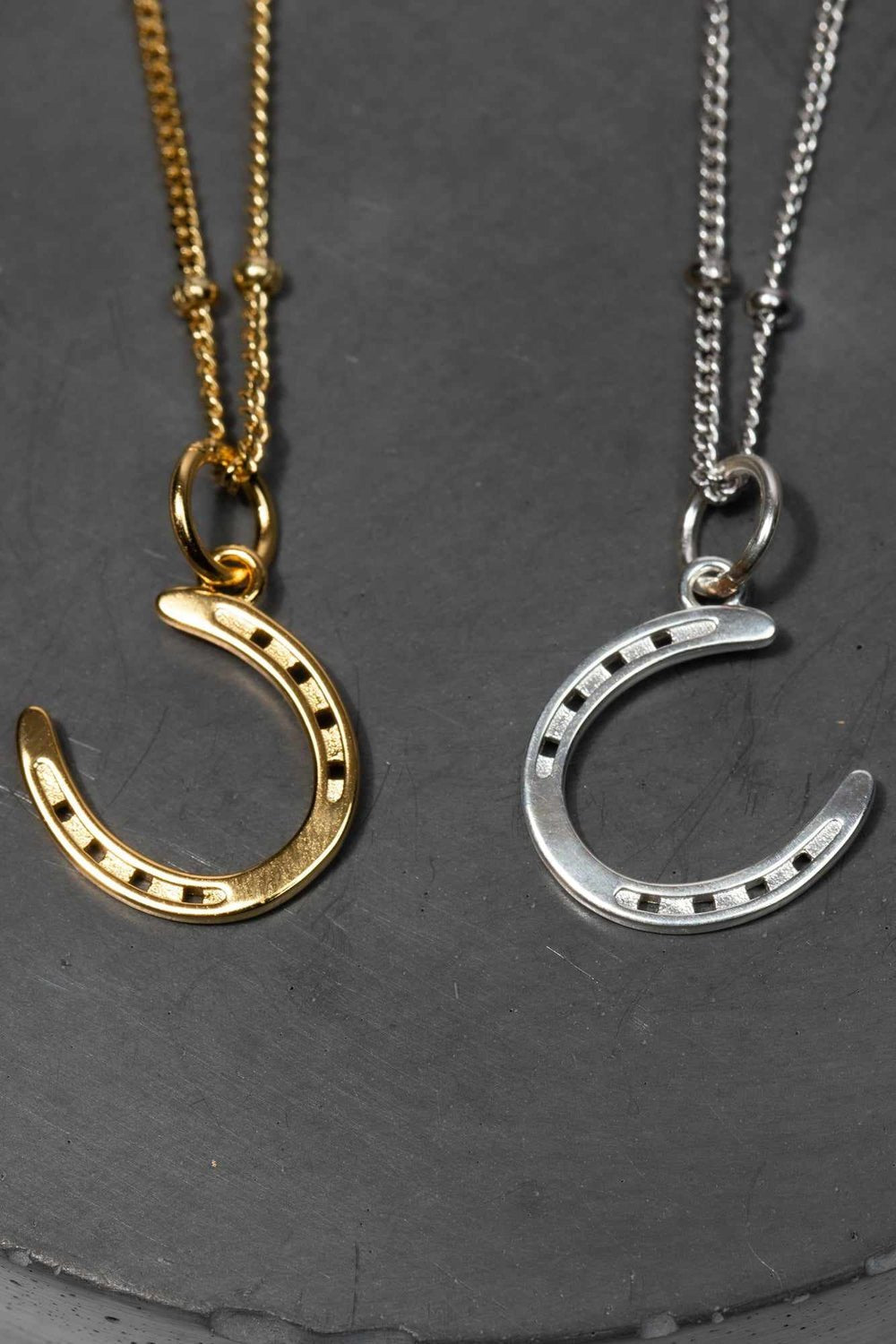 A pair of gold and silver horseshoe necklaces, symbolizing luck and elegance in a stylish design. 
The necklace chain is also gold and silver respectively, chain has a series of small, rounded beads interspersed along its length . Crafted from high-quality gold and silver,  ideal for horse fans, pony lovers, show jumping, equestrian life and fans of equestrian inspired jewelry, gold girls and silver girls.