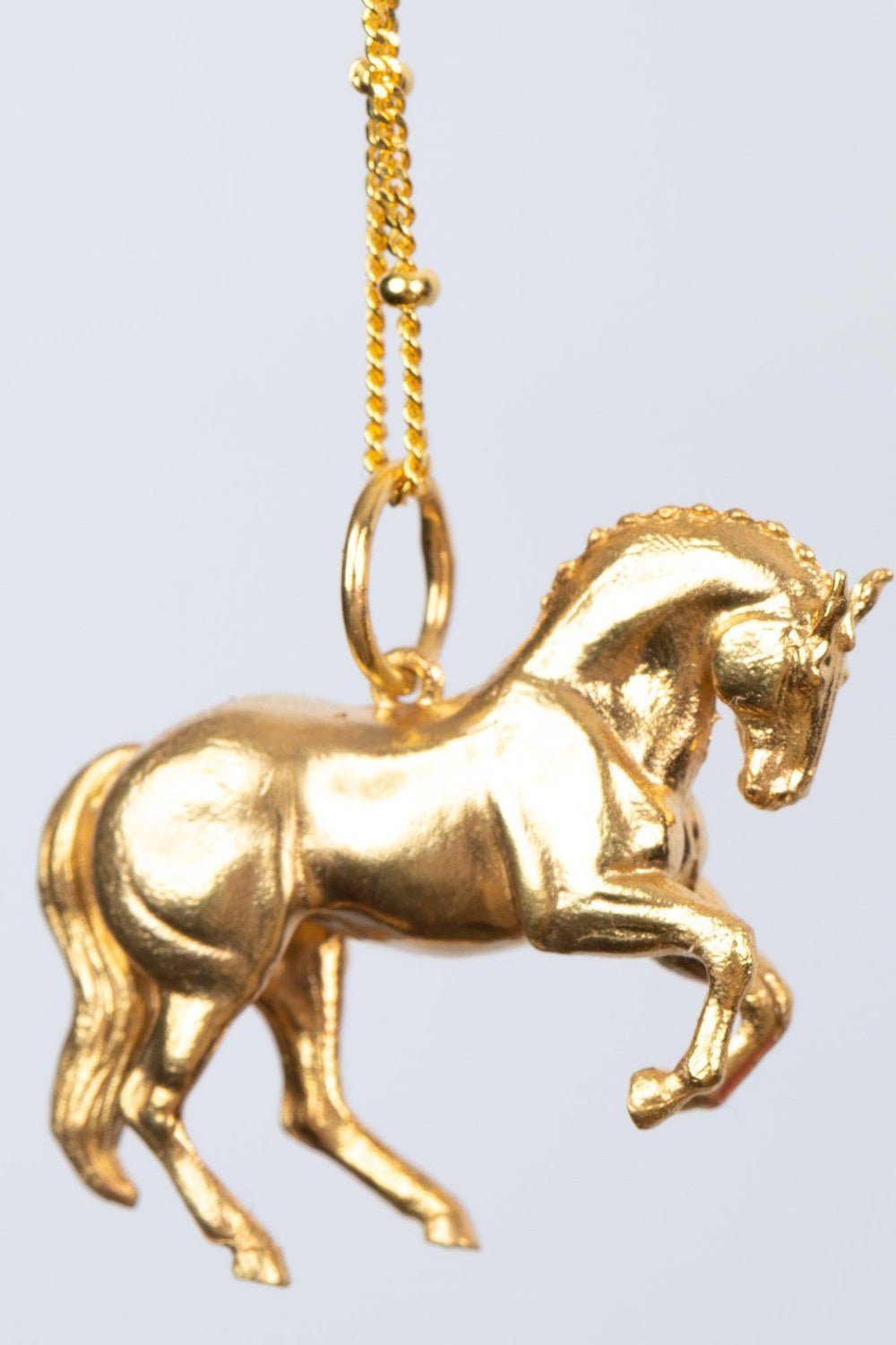 Our perfect horse pendant. a gold horse pendant elegantly displayed, showcasing its intricate design and craftsmanship.The pendant is shaped like a wild horse in mid-stride, with detailed features such as its mane and tail.    Perfect for horse lovers, fans of equestrian inspired jewelry, horseback riders, silver horse jewelry, unique equine gifts, horse girls. A dynamic piece of Horse Jewelry.