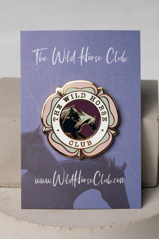 Enamel pin featuring two horses on a purple card. Text on pin reads: The Wild Horse Club. Perfect for horse girls, horse riders, show jumping, horseback riders and more. This pin design  is a cool equestrian gifts. A colorful flower with a clover, this enamel pin representing the wild horse club, highlighting the beauty and spirit of wild horses.